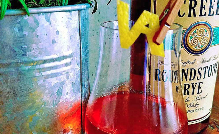 large glass of red cocktail with VA clipped on