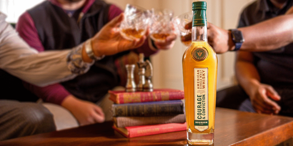 Bottle of Virginia Distillery Company Whisky with hands holding glasses in the back