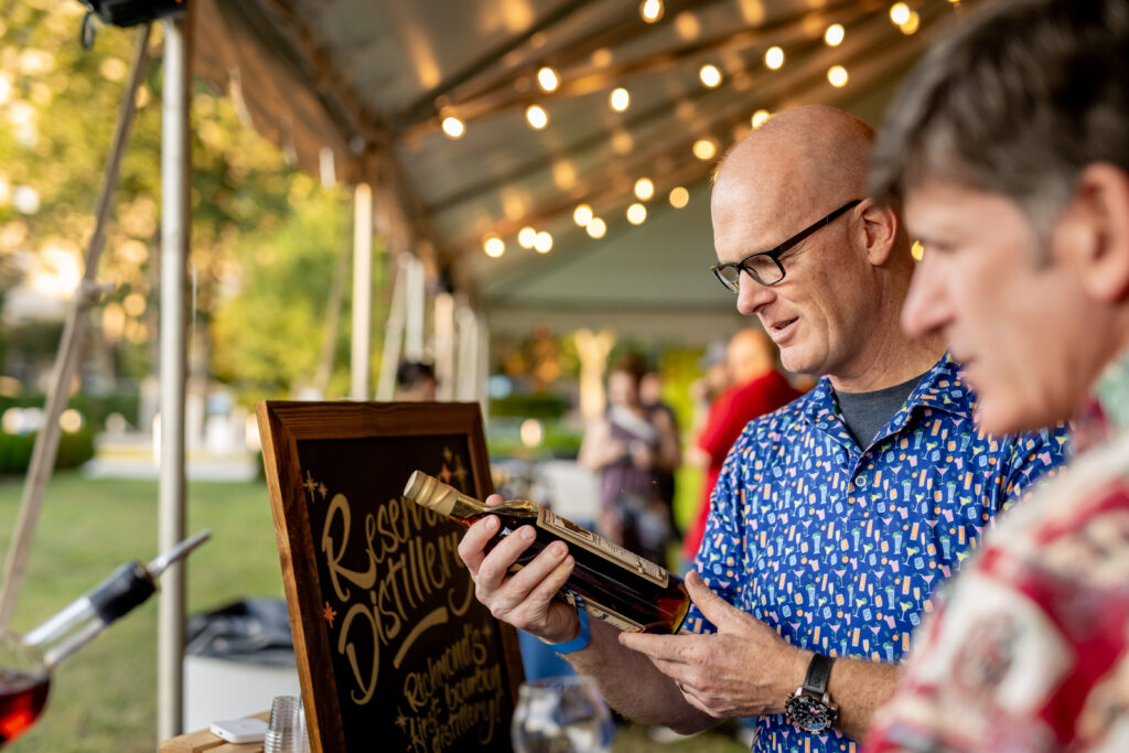 Attendees at Virginia Distilled peruse Virginia spirits bottles during Virginia Spirits Month