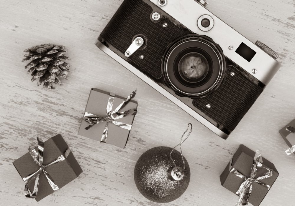 A grayscale shot of Christmas gift boxes and camera